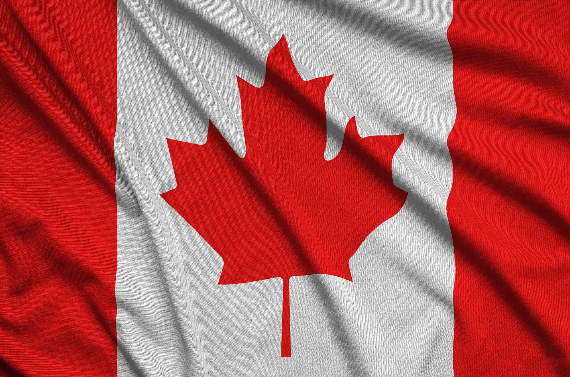 Canada flag is depicted on a sports cloth fabric with many folds. Sport team waving banner