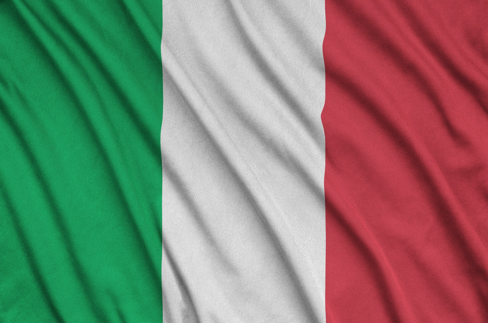 Italy flag is depicted on a sports cloth fabric with many folds. Sport team waving banner